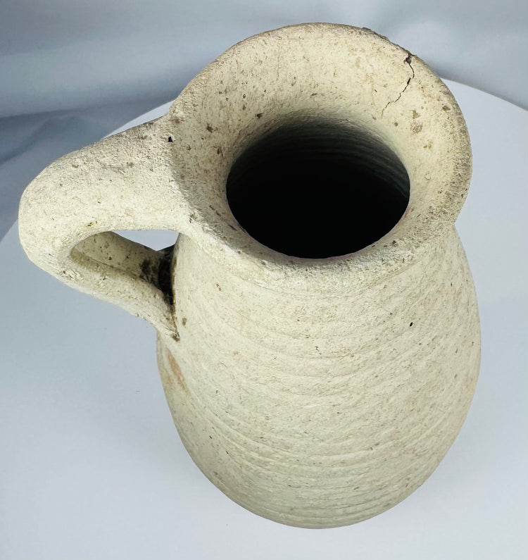 Side profile of an Ancient Roman terracotta pitcher showing the loop handle, neck, and rounded body.