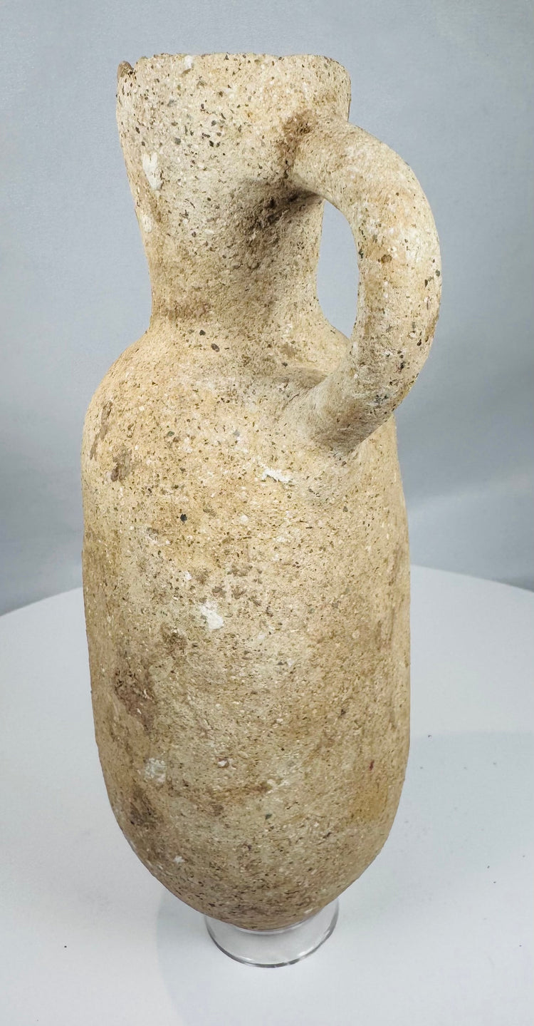 Ancient Mediterranean terracotta pouring jar displaying coarse buff-colored clay and natural mineral deposits.
