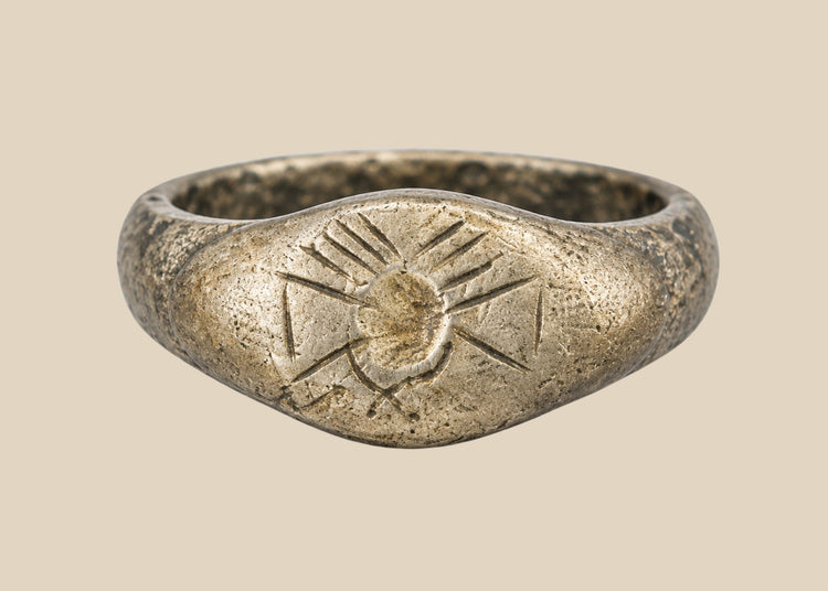 Ancient silver signet ring with finely engraved sunburst motif on bezel, thin rounded band, and natural aged patina, dating to the Late Roman to Early Byzantine period, circa 200–500 CE.