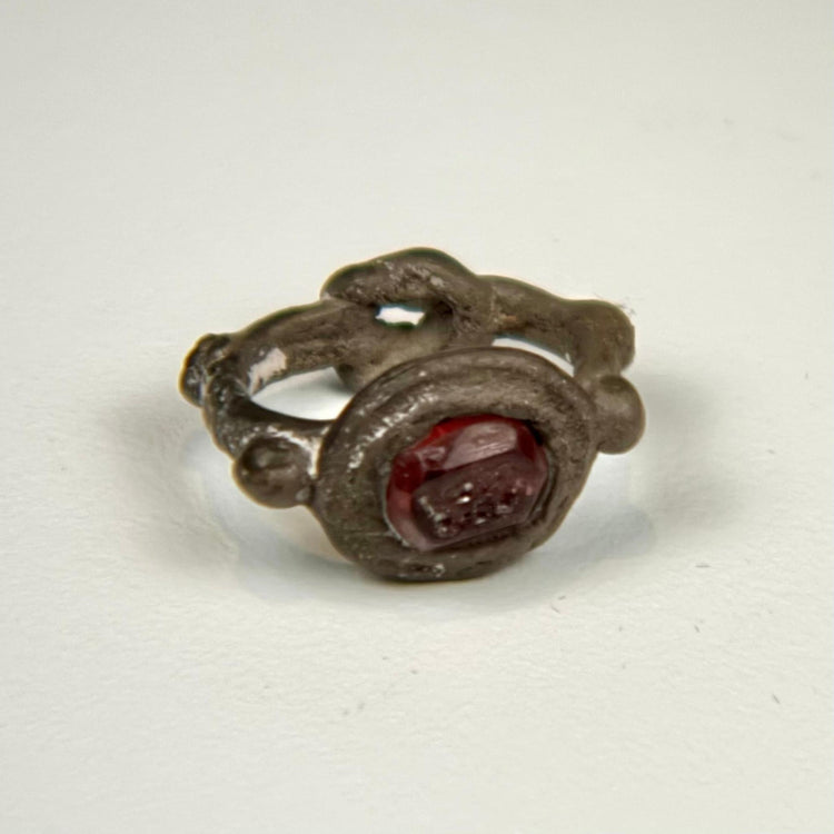 Late Roman silver ring with deep red garnet intaglio and decorative raised bezel, circa 300–600 CE