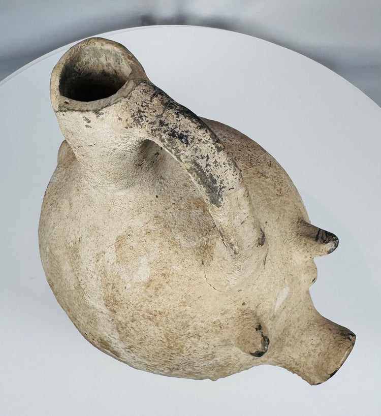 Side profile of an Early Bronze Age Anatolian terracotta pig vessel highlighting the tripod support legs.