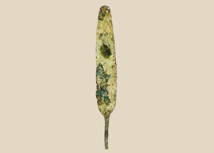 Ancient bronze spearhead from the Early to Late Bronze Age (circa 3300–1200 BCE). Leaf-shaped blade with tapered point, mounted on a modern display base. Exhibits natural patina and surface oxidation, reflecting early metallurgical craftsmanship and use in hunting or combat.