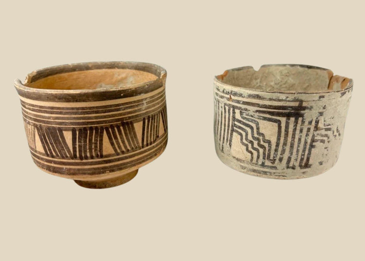 Pair of ancient Harappan terracotta pottery vessels from the Indus Valley Civilization, decorated with bold black geometric linear and zigzag motifs; hand-crafted, wide-bodied bowls with rimmed edges, dating circa 2600–1900 BCE, showing surface wear, minor chipping, and aged earthen patina consistent with archaeological finds.