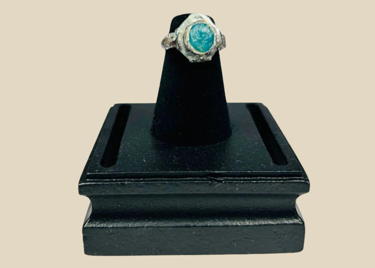 Ancient silver ring from the Near East or Mediterranean, 1st millennium BCE, featuring an engraved prancing horse with mounted rider and a raised turquoise bezel. Silver band with natural patina highlights fine ancient metalworking, symbolizing nobility, strength, and protective talismanic power.