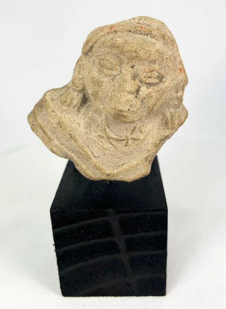 Terracotta fragment of a stylized anthropomorphic figure with almond-shaped eyes, prominent nose, and incised chest details, mounted on a modern wood base; likely from West Mexico (Nayarit or Jalisco) or Iberian/Roman provincial context, circa 200 BCE–2nd Century CE.