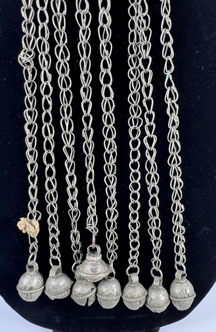 Afghan tribal pendant displaying handcrafted silver-toned metalwork, red glass accents, and ceremonial chain tassels.