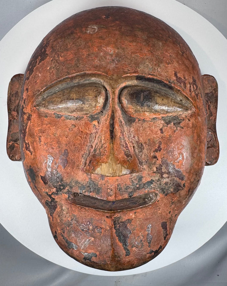 Traditional tribal wooden mask displaying abstract facial forms and authentic aged wear