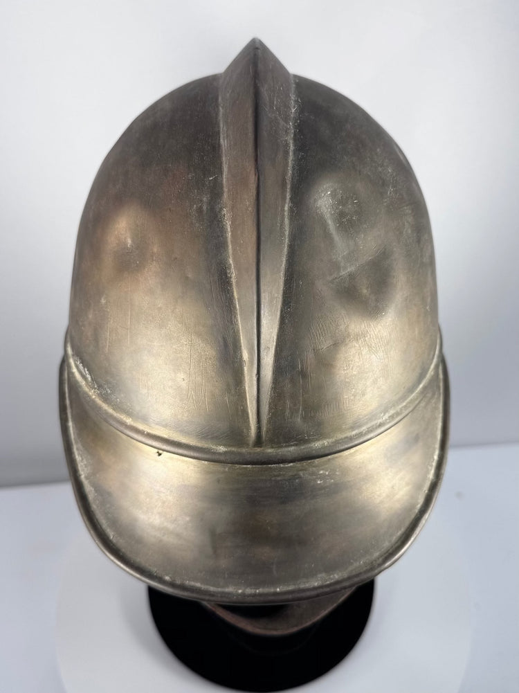 Antique German firefighter helmet showing brass shell, broad brim and leather chinstrap, circa 1908–1934