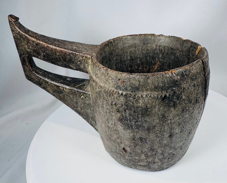 Hand-carved tribal wooden bowl with elongated handle and deep hollowed interior basin
