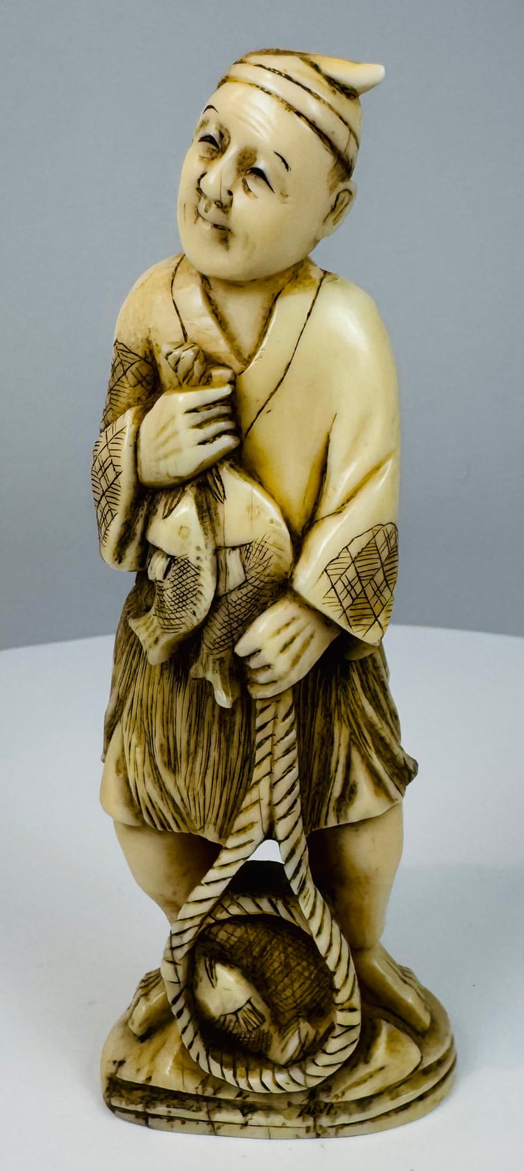 Rear three-quarter view showing the fisherman’s patterned garment and carved basket