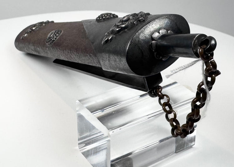 Japanese matchlock gunpowder flask displayed horizontally with floral decoration, chain and long carrying clip