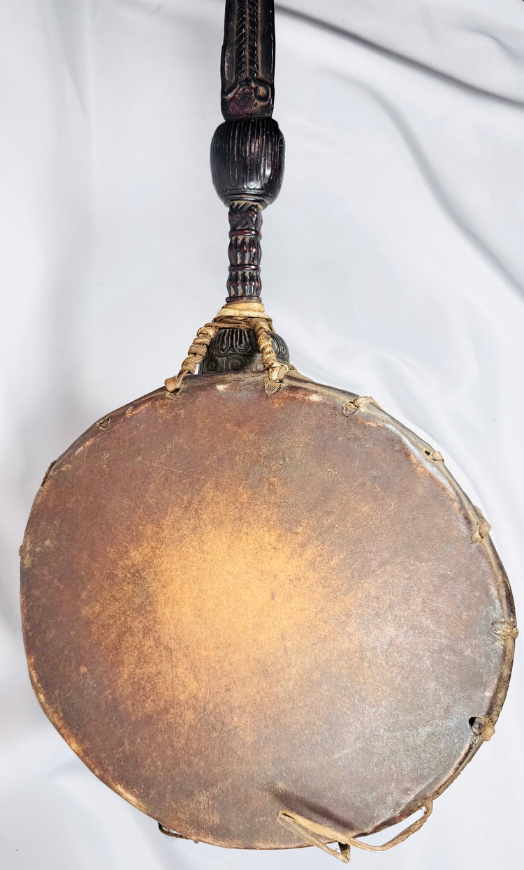 Antique Himalayan ritual percussion instrument with carved anthropomorphic finial and rawhide lacing.