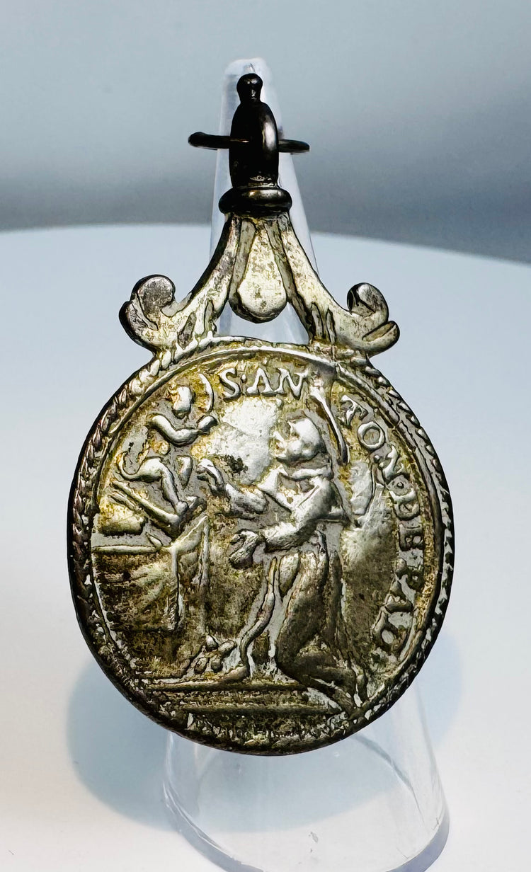 Reverse of a Catholic devotional medal displaying the IHS Christogram and symbols of Christ's Passion.