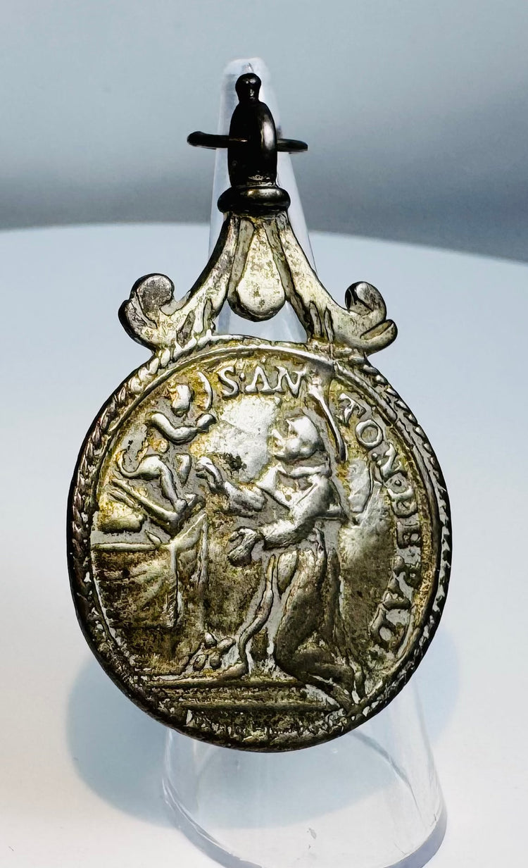 Reverse of a Catholic devotional medal displaying the IHS Christogram and symbols of Christ's Passion.