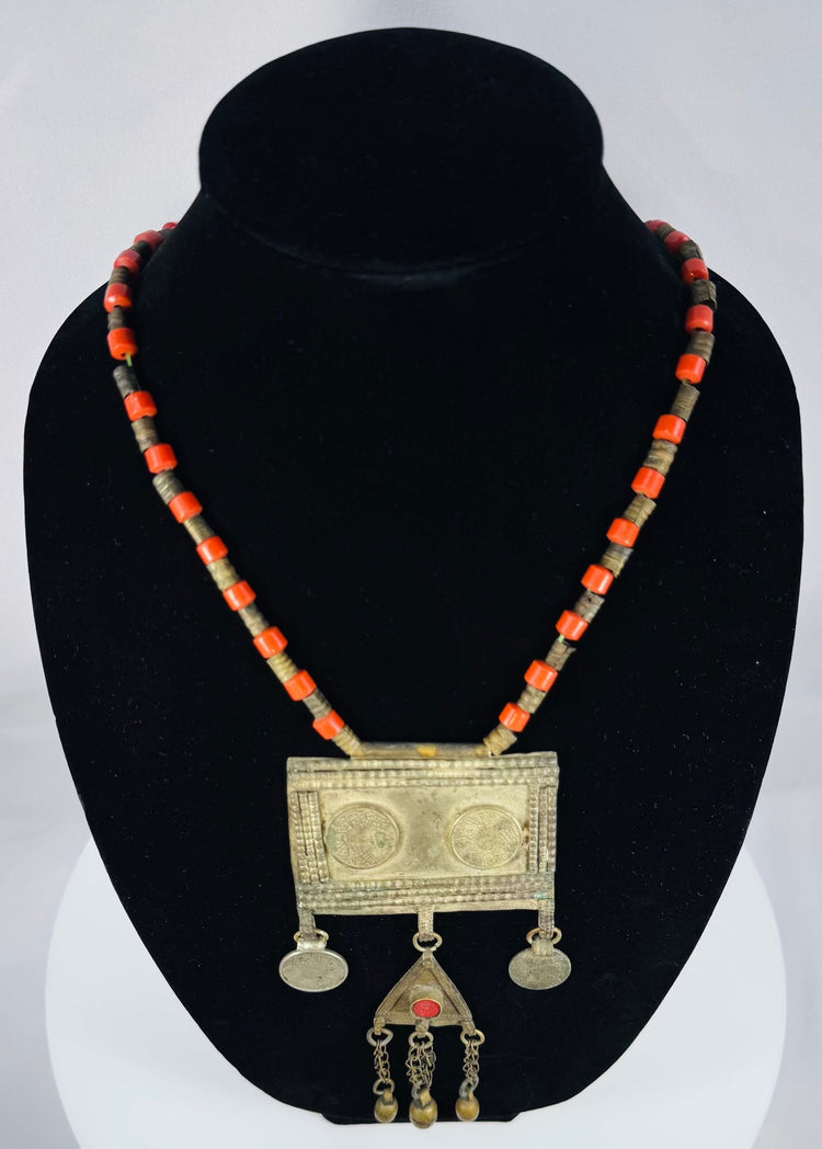 Historic Turkmen tribal necklace displaying traditional Central Asian jewelry with coin elements, red glass accents, and ornate metalwork.