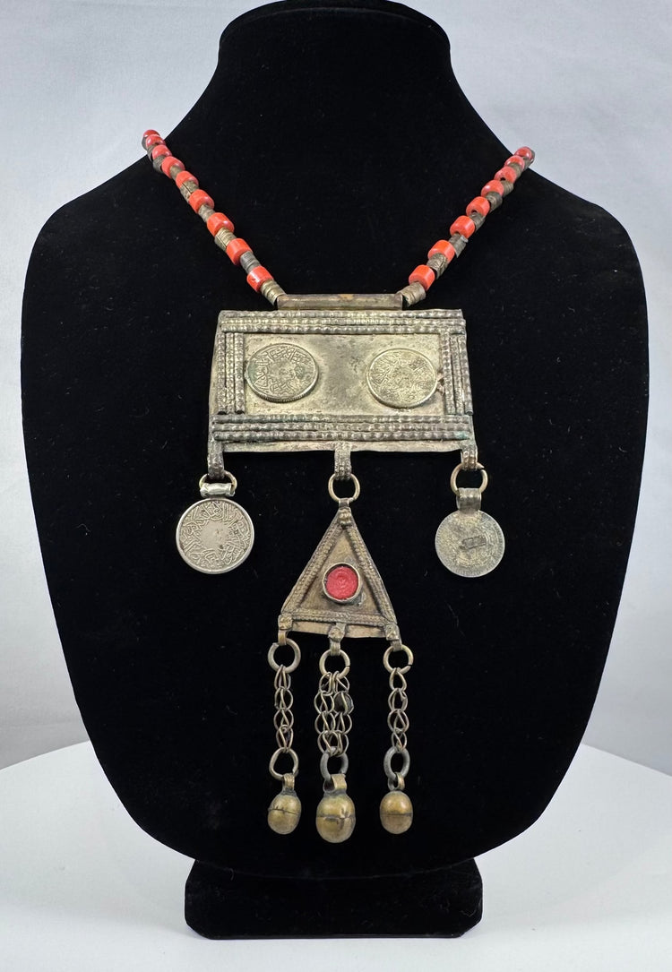 Antique Turkmen tribal jewelry with suspended coin elements, red glass beads, and handcrafted silver-toned metalwork.
