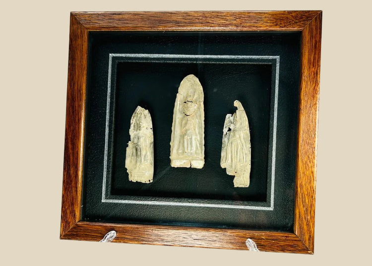 Framed set of three antique cast metal votive plaques from Cambodia or Thailand, 16th–17th Century CE. Central plaque depicts a seated Buddha in meditation, flanked by attendant or deity figures, with intricate engraved details. Mounted on a custom wooden frame, showcasing devotional artistry and Theravāda Buddhist iconography.