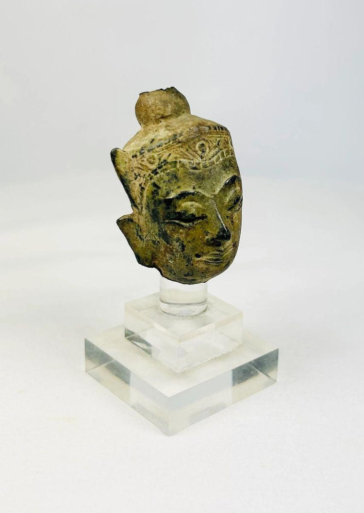 Fragmentary cast bronze Buddha head with serene expression, arched brows, closed eyes, subtle smile, and engraved crown band; traces of gilt and lacquer; likely Thailand or Burma, Late Ayutthaya–Early Rattanakosin or Toungoo–Konbaung period, circa 15th–18th century CE; mounted on a custom acrylic stand.