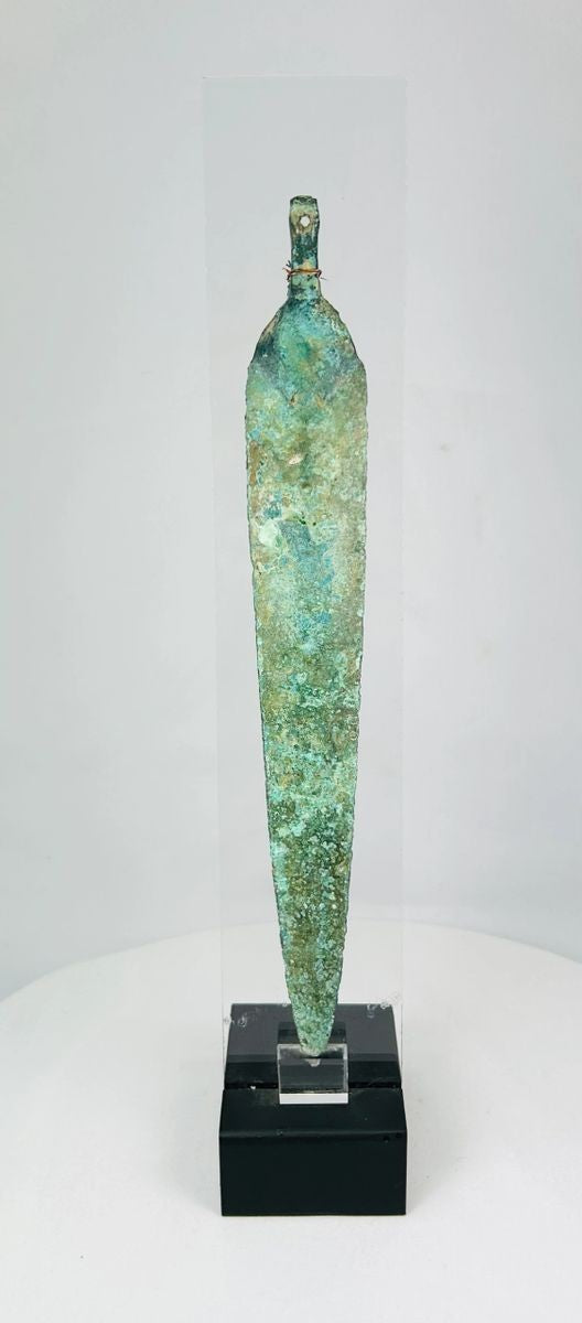 Ancient Western Asiatic bronze dagger blade, 1st millennium BCE, with tapered form, central spine, perforated base, and green patina.