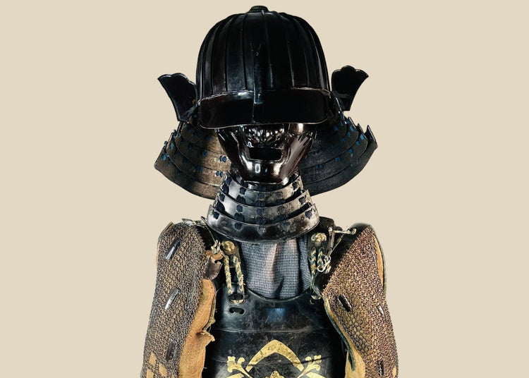 Authentic Japanese samurai armor set from the Muromachi Period (1333–1573), featuring a black-lacquered 24-plate suji-bachi kabuto helmet, menpo facial armor, gold-painted mon on the cuirass, Edo-period silk lacing, and chainmail sleeves, displayed on a wooden stand against a white background