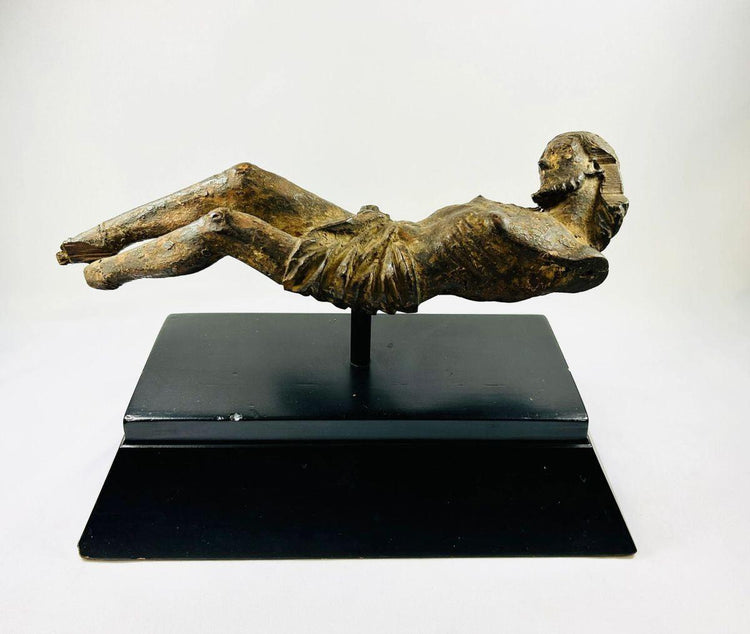 Side view of the fragmentary Baroque corpus showing the carved torso, bowed head, loincloth, and aged surface