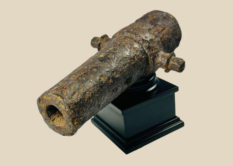 Rusted miniature iron cannon from the British Civil War period, mounted on a black display stand, featuring original trunnions and hollow barrel, 17th century.