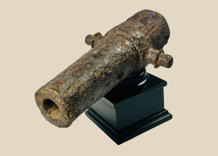Rusted miniature iron cannon from the British Civil War period, mounted on a black display stand, featuring original trunnions and hollow barrel, 17th century.