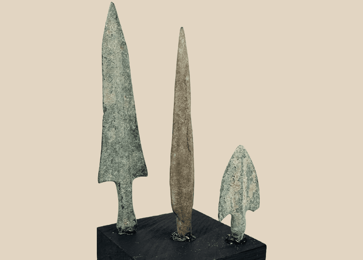 Three ancient Western Asiatic bronze projectile points mounted on a black display base