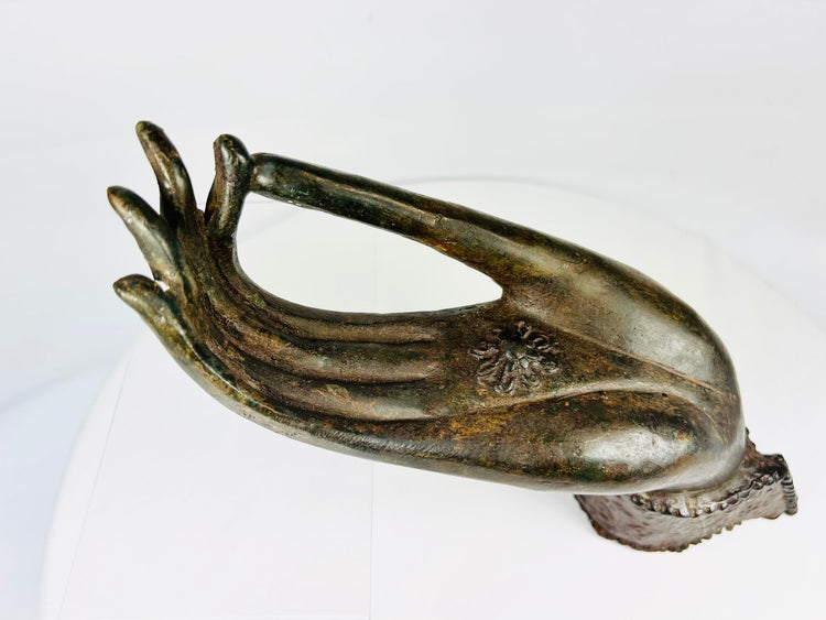 Northern Thai Buddhist bronze hand with symbolic chakra motif, antique fragment on display stand.