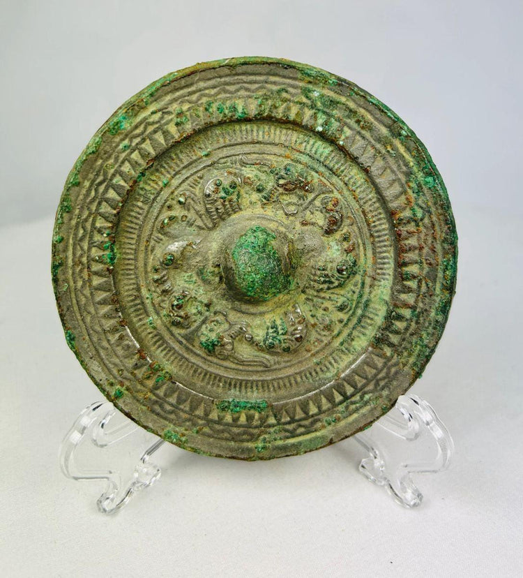 Han Dynasty bronze mirror, circa 206 BCE–220 CE, with engraved geometric and mythical motifs, central suspension knob, and rich green patina.