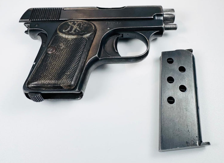 Browning Model 1906 pocket pistol beside a detached metal magazine with circular inspection holes.