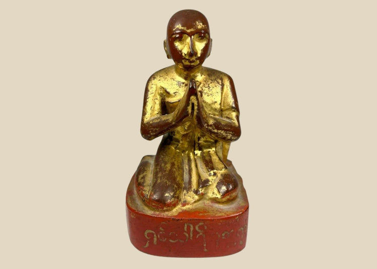 19th-century Burmese wooden monk statue with gold leaf and lacquer remnants, kneeling in Anjali Mudra with serene expression and inscribed base.