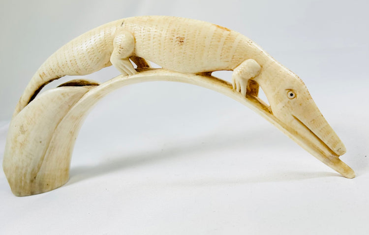 Detailed view of an African hippopotamus tooth carving depicting a crocodile motif, handcrafted early 20th-century ivory artwork displayed on a white background.