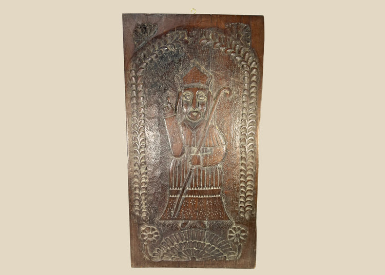 Hand-carved hardwood devotional panel depicting a bishop saint, likely St. Nicholas, with crozier and blessing gesture, foliate border with rosettes, Central/Eastern Europe, c. 1780–1830, 18 7/8 x 9 3/4 inches