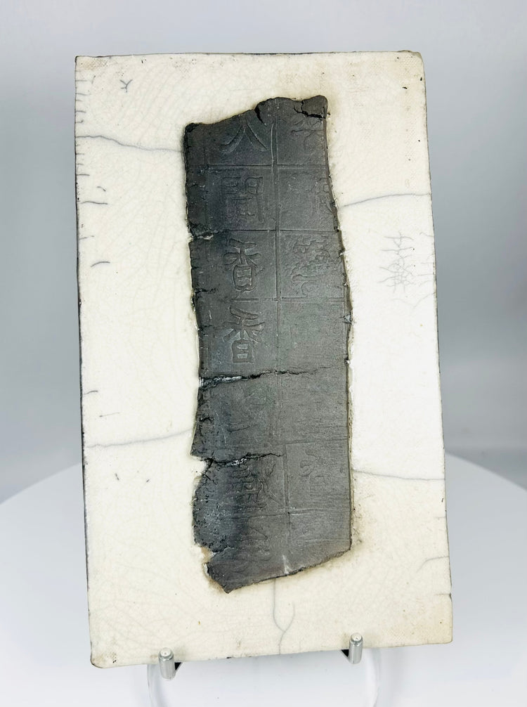 Chinese inscribed ceramic fragment displayed on stand highlighting texture, patina, and incised characters