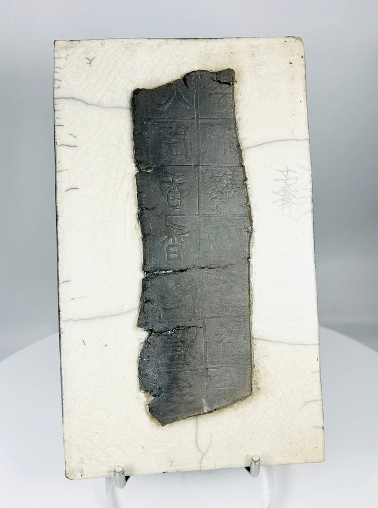 Chinese inscribed ceramic fragment displayed on stand highlighting texture, patina, and incised characters