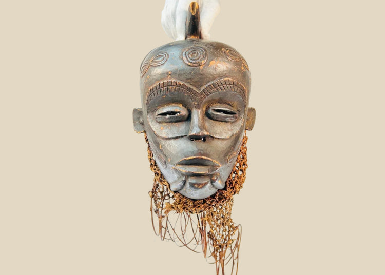 Chokwe wooden ceremonial mask from Central Africa with serene closed eyes, geometric forehead motifs, and wickerwork fiber adornments, 19th–20th century CE.