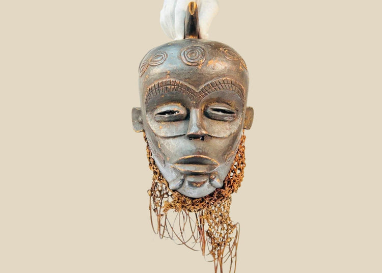 Chokwe wooden ceremonial mask from Central Africa with serene closed eyes, geometric forehead motifs, and wickerwork fiber adornments, 19th–20th century CE.