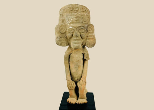 Mesoamerican Classic Period terracotta figure from Teotihuacan sphere with tall cylindrical headdress, incised roundels and step-fret band, large disk earspools, hands-on-knees posture, buff/orange clay with mineral accretions, mounted on modern black wood block, ca. 250–600 CE.