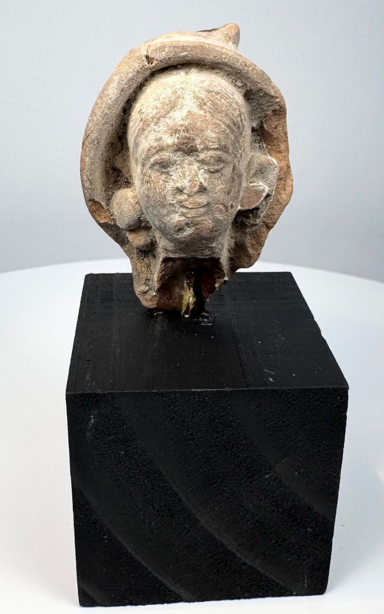 Ancient Greek or Roman terracotta head fragment from the Mediterranean, featuring a serene classical face and weathered surface.