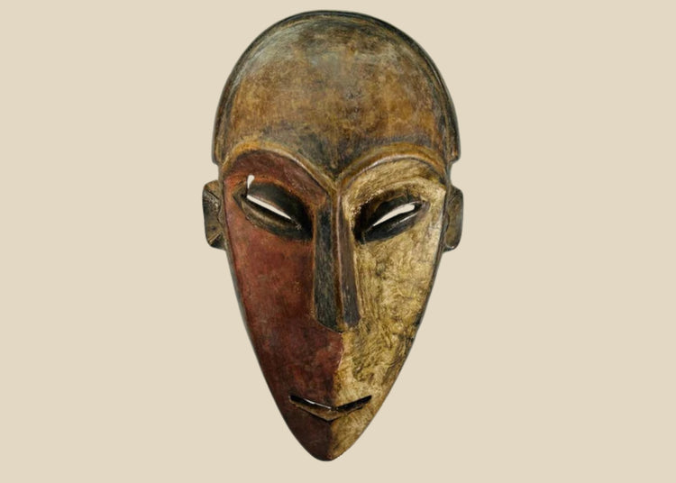 Authentic Dan tribal mask from Côte d’Ivoire, carved wood with dual-tone pigments, elongated eyes, and patina from ritual use, circa 1930–1950.