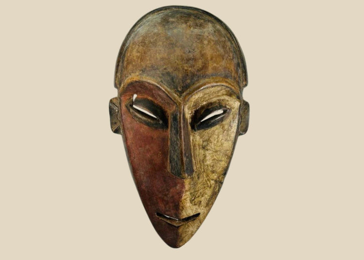 Authentic Dan tribal mask from Côte d’Ivoire, carved wood with dual-tone pigments, elongated eyes, and patina from ritual use, circa 1930–1950.