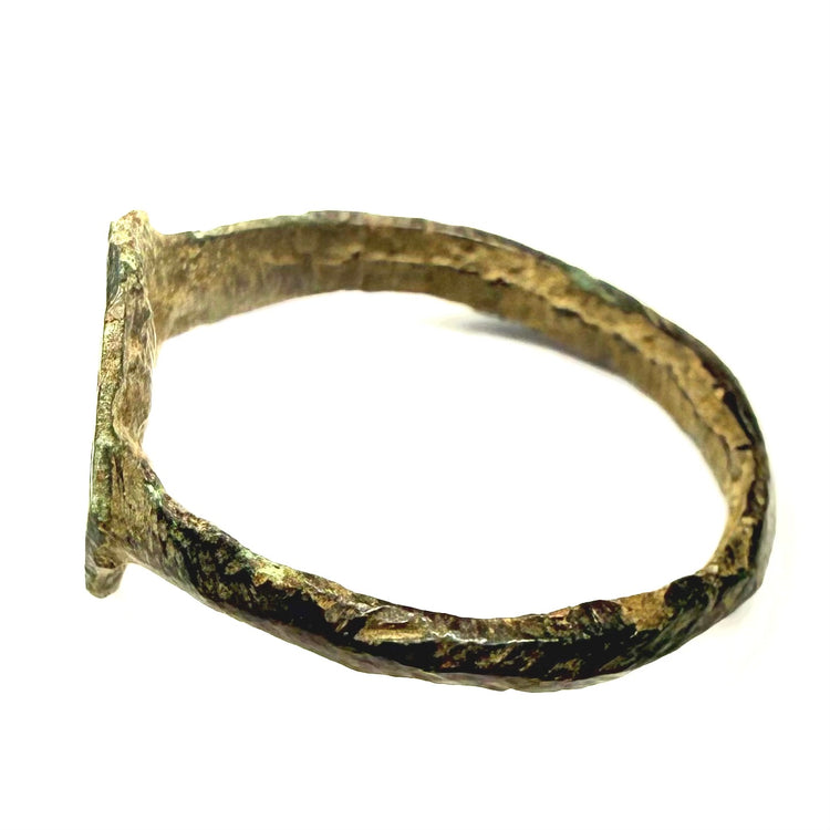 Side view of ancient bronze ring showing narrow hoop with repeated oblique incised decoration