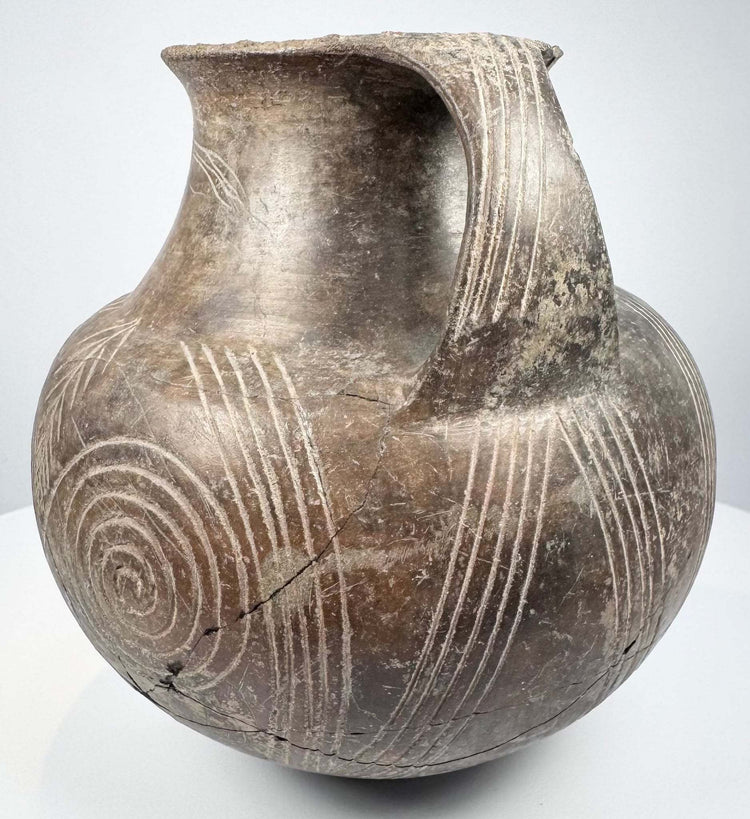 Detail of single large spiral decoration and vertical incised lines beneath curved handle
