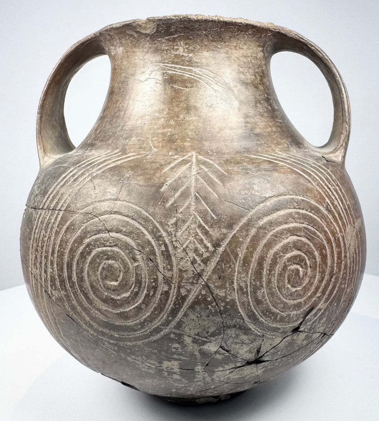 Opposite side of the impasto amphora with one handle prominent and concentric spirals extending across the lower body.