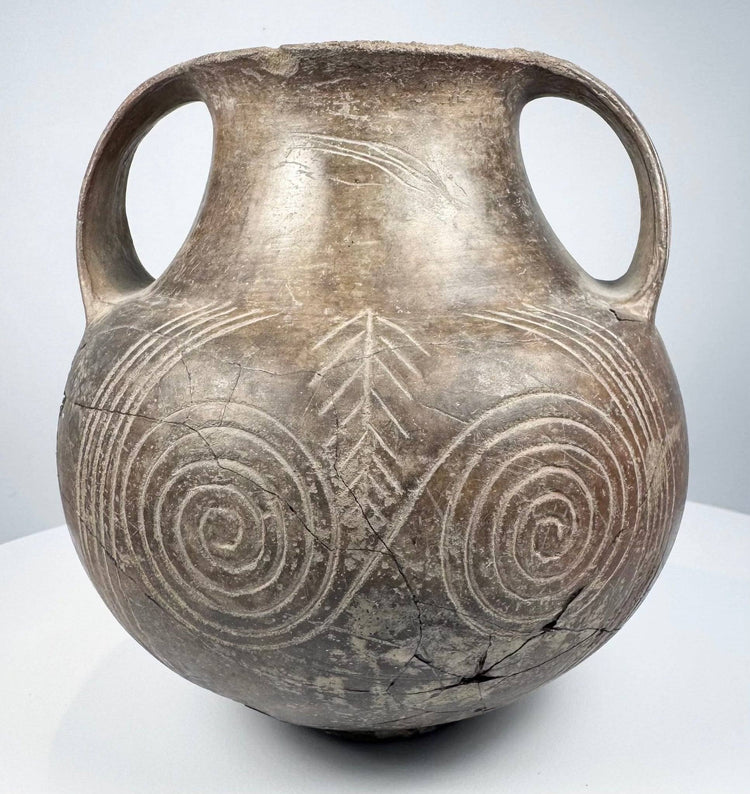 Ancient Etruscan terracotta amphora showing its rounded body, high loop handles, short neck, and dark impasto surface.