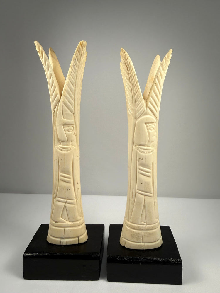 Pair of Egyptian-style carved bone candlestick holders with lotus and papyrus motifs on black display bases