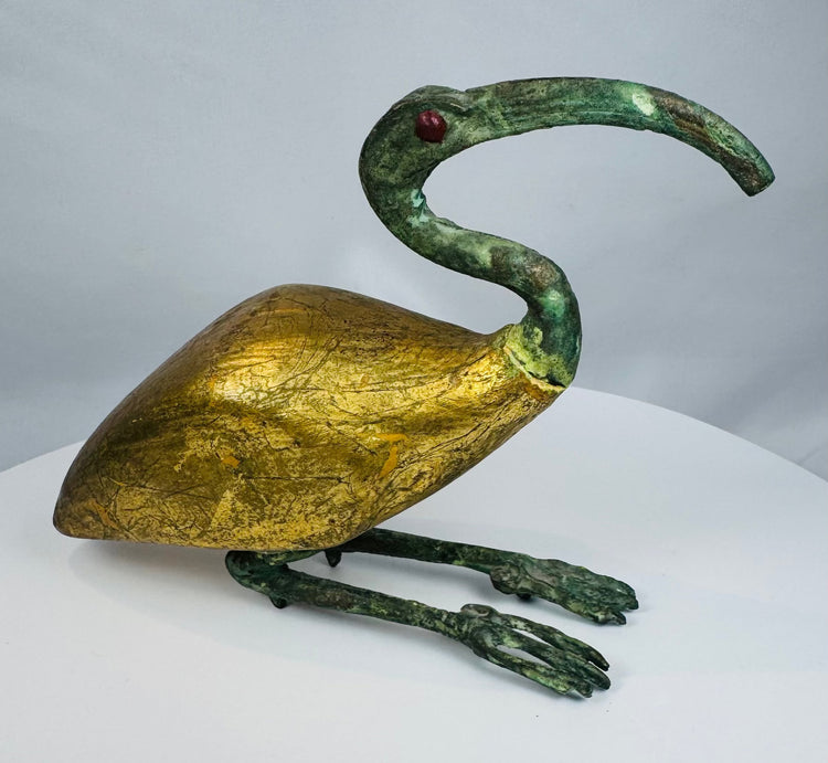 Side view of an Egyptian Revival sacred ibis sculpture displaying its gilt body and long patinated legs.