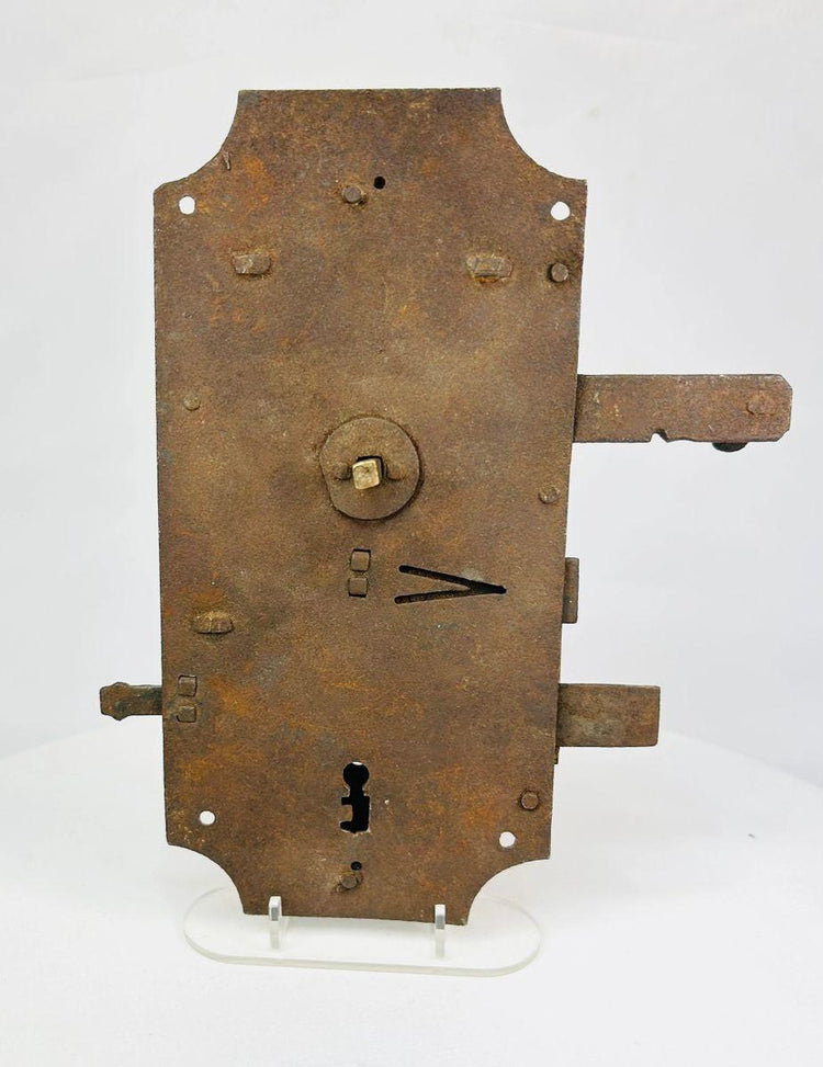 18th-century European hand-forged iron door lock with rectangular form, exposed keyhole, scroll springs, and aged patina.