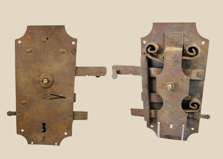 18th-century European hand-forged iron door lock with rectangular form, exposed keyhole, scroll springs, and aged patina.